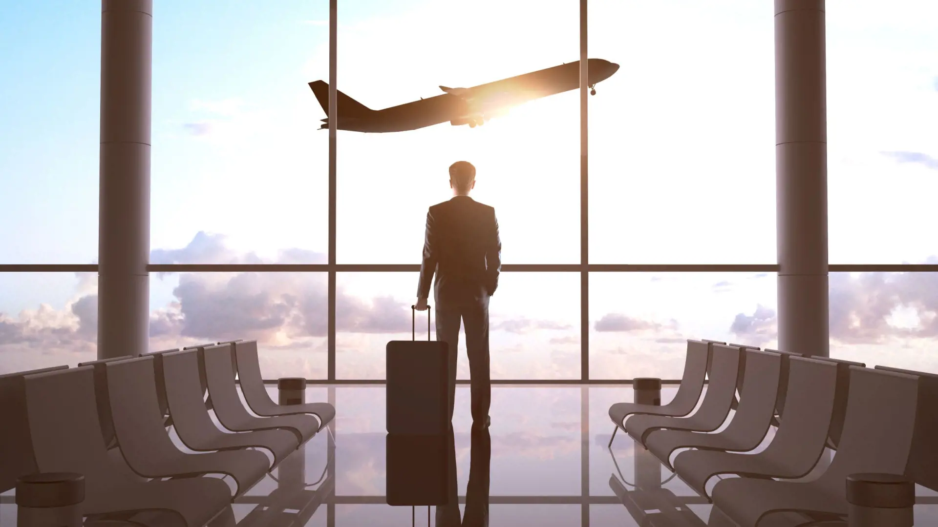 Image of a business person looking out of an airport window at a plane taking off